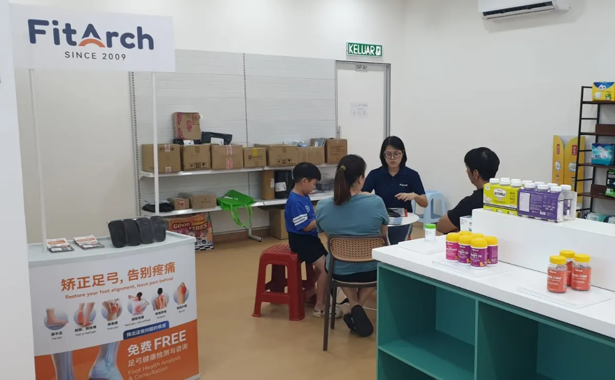 FitArch 在 Johor Bahru 合作门店内，工作人员与一家人坐着交流的咨询场景